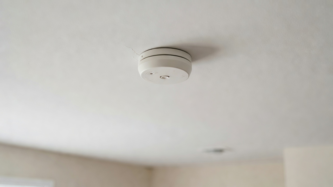 A smoke detector mounted on a painted residential ceiling