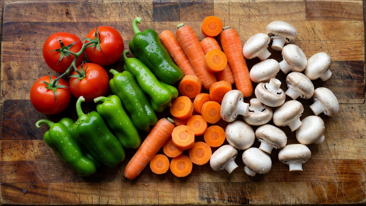Overhead view of a scarred wooden cutting block holding fresh vegetables
